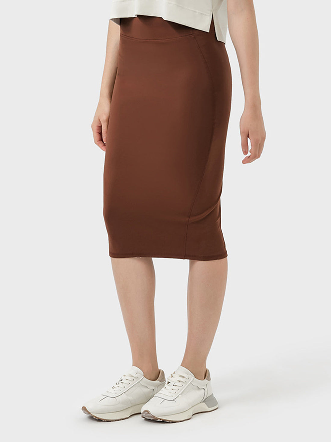 Back view of a brown active wrap skirt with a slit on a model wearing sneakers.