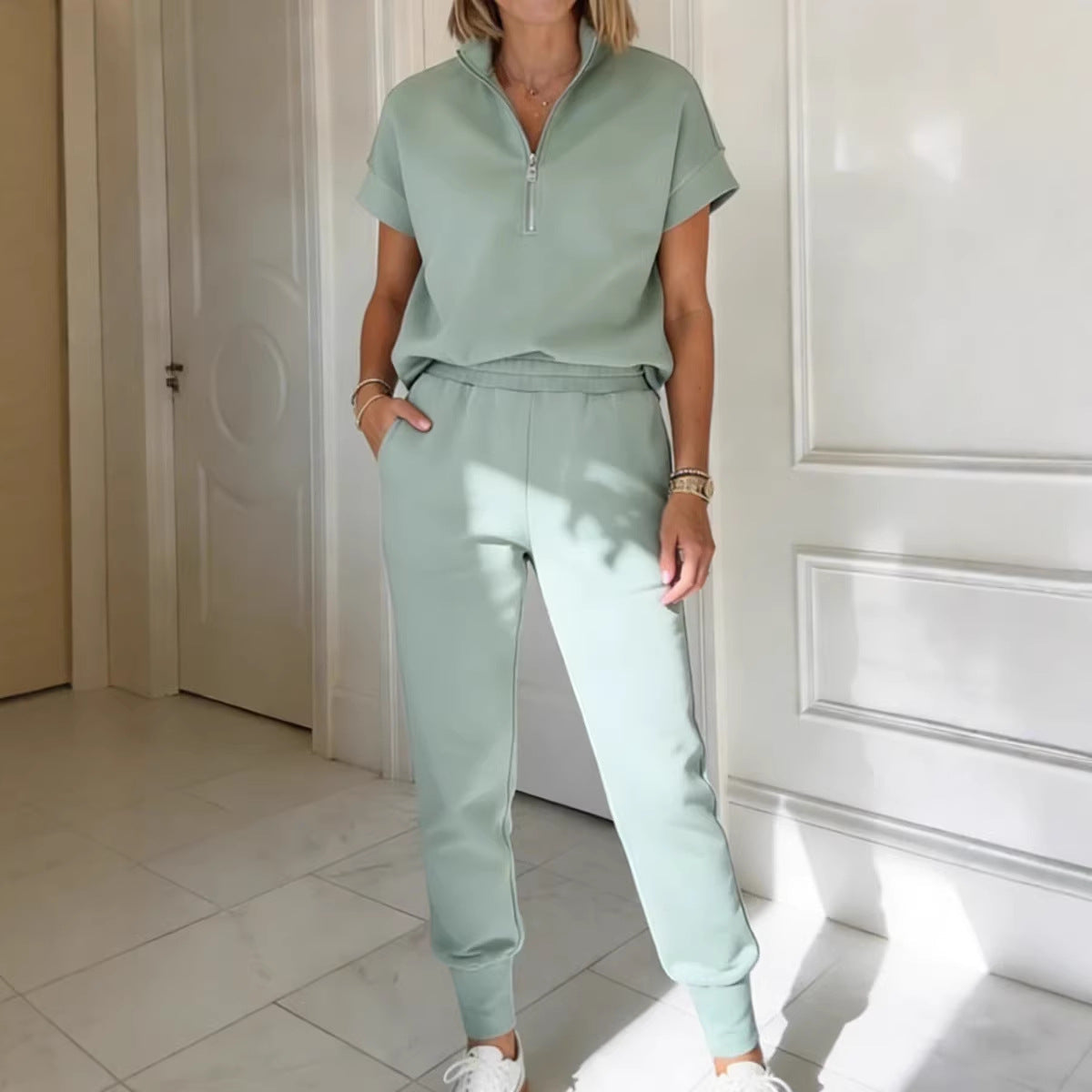 Woman wearing a light green short sleeve quarter-zip top and matching slim-fit jogger pants