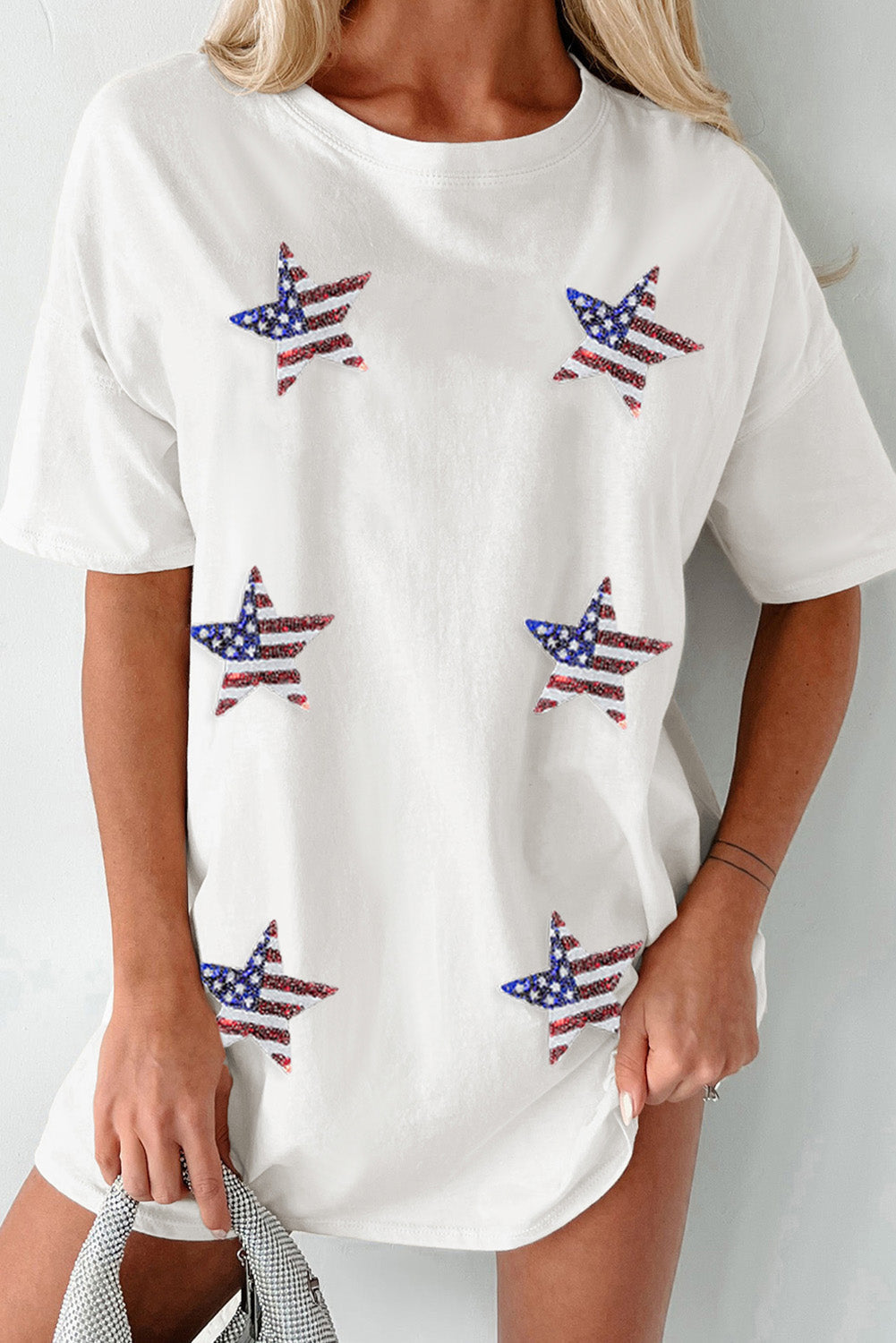 A woman wearing a white oversize t-shirt with sequin stars in a USA flag pattern.