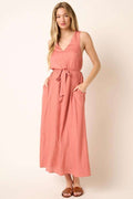 Woman wearing a chic V-neck maxi dress with a belted waist and elegant cross-back detail