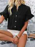 Woman wearing a button-down short sleeve shirt with ruffled and ruched details