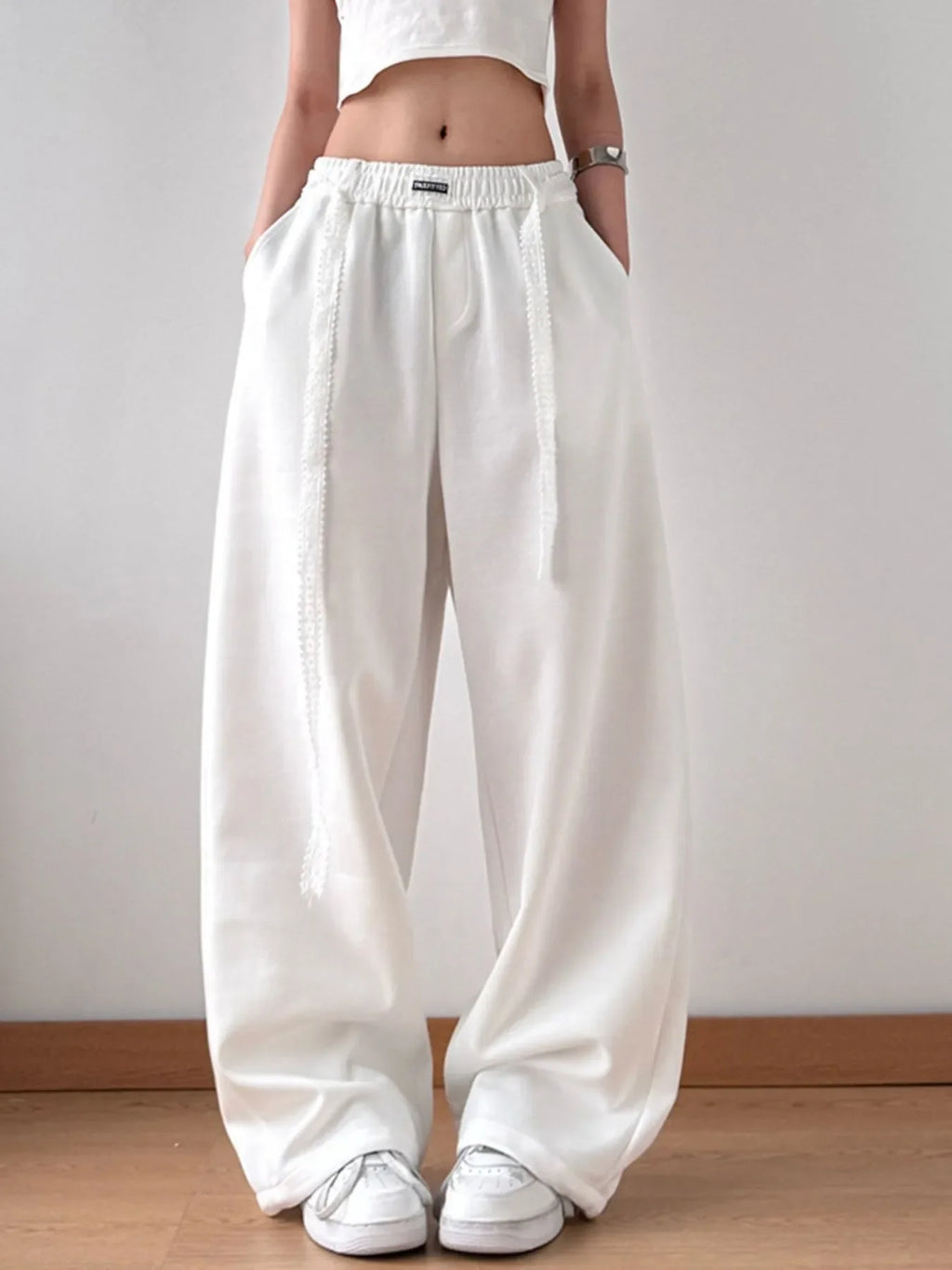 Model wearing white wide-leg pants with elastic drawstring waist and side pockets