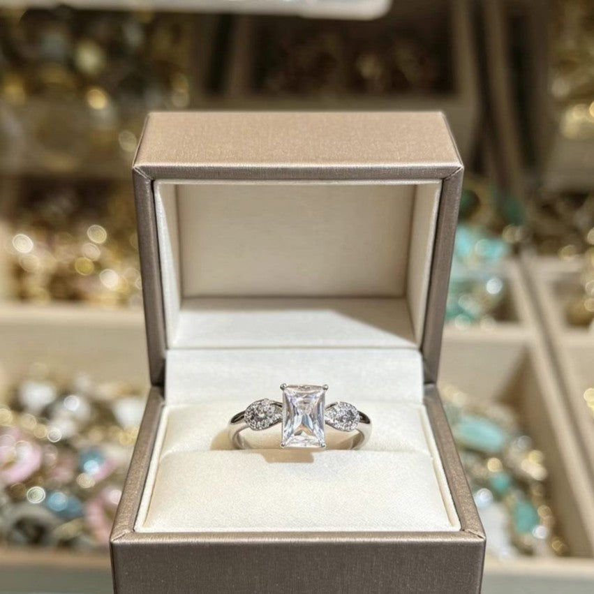 Minimalist square sugar cube style adjustable ring in polished silver with emerald and pear-cut clear cubic zirconia accents.