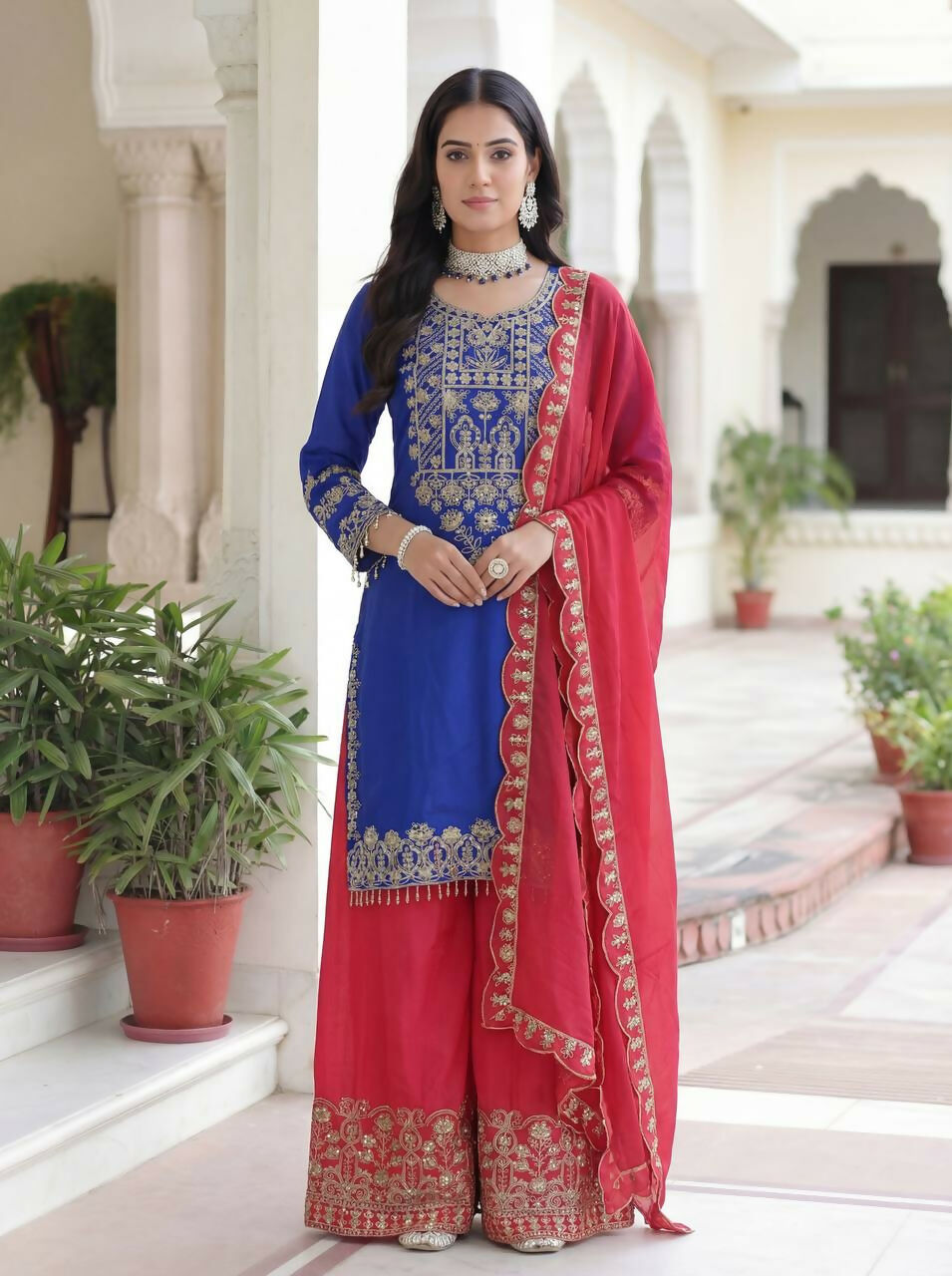 Woman wearing a blue silk embroidered kurti and sharara set with matching dupatta
