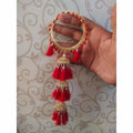 Red silk thread bangles with hanging pearls and gold-toned jhumka charms for bridal wear