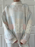 Model wearing a pastel blue quilted mockneck sweatshirt with a relaxed unisex fit.