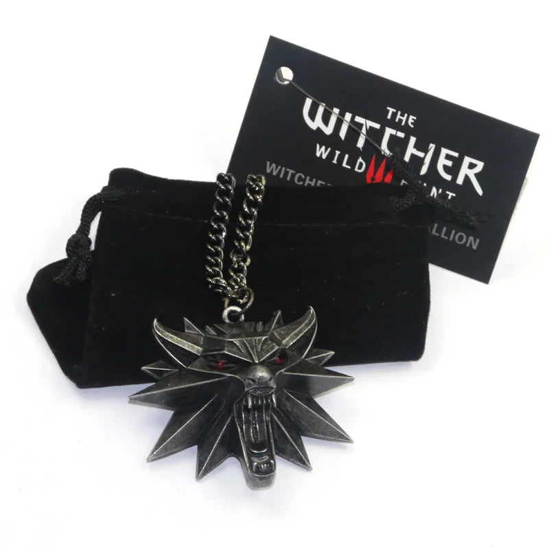 Front view of The Witcher 3 Wild Hunt Wolf Head Medallion Necklace with dark metal finish and red eyes, resting on a black velvet pouch.