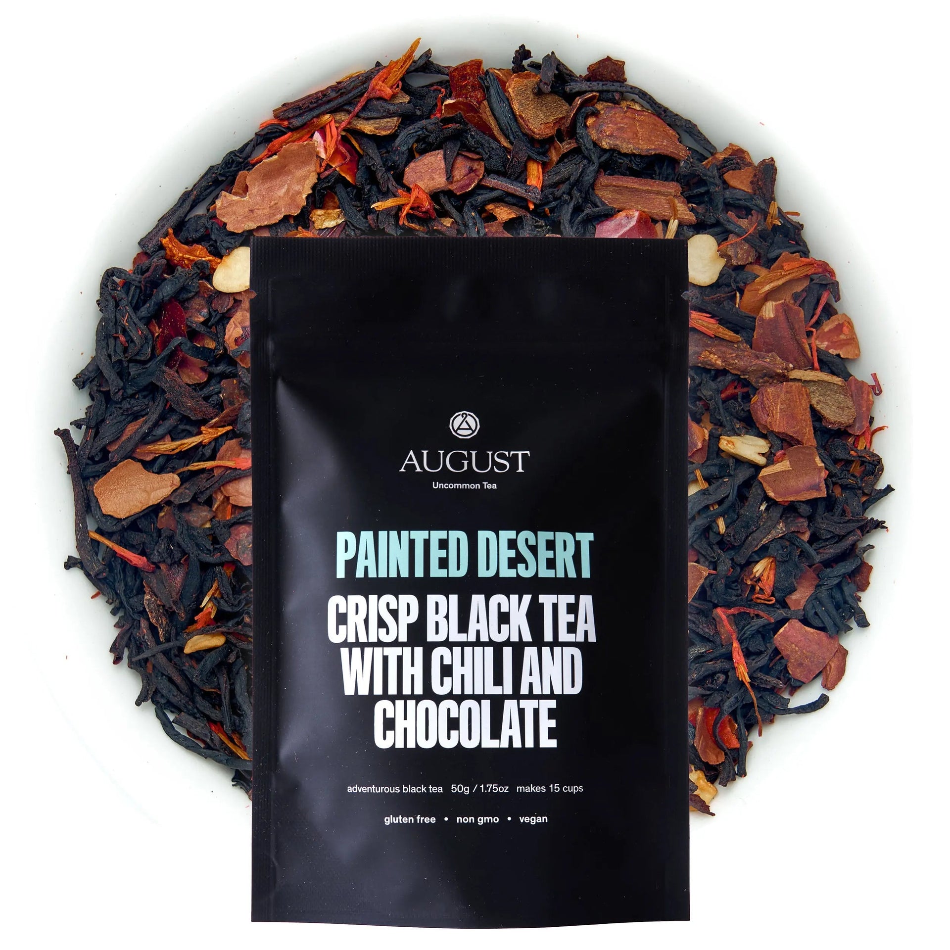 A pouch of Painted Desert black tea surrounded by loose tea leaves containing dried chili, cacao shells, and cinnamon.