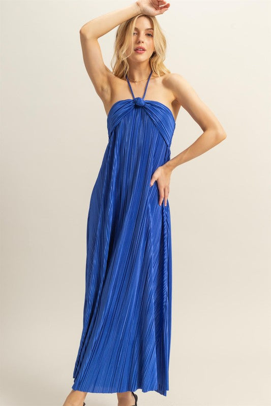A woman wearing a royal blue halter neck maxi dress with a knotted front detail.