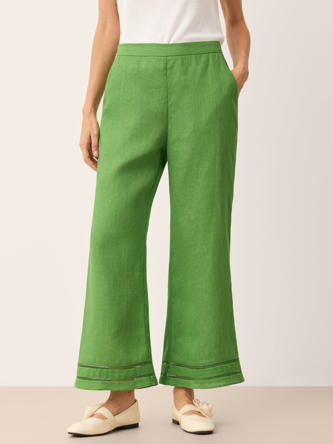 Model wearing NERINA 100% linen cropped flare pants with delicate double lace-trim hems and an elastic waist.