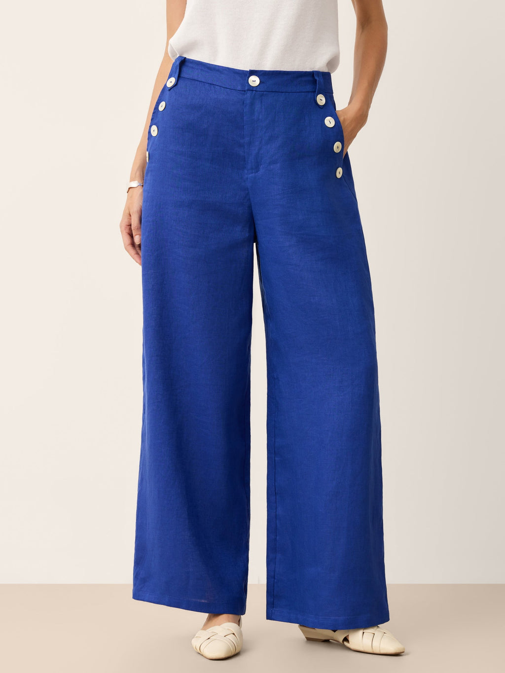 Close up of IONE 100% linen wide-leg pants highlighting the luminous shell button accents and high-waist design.