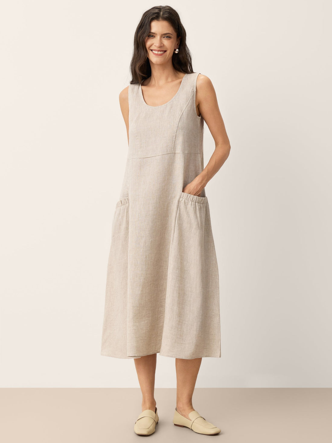 Model wearing a 100% linen sleeveless scoop neck swing maxi dress in a beach setting.
