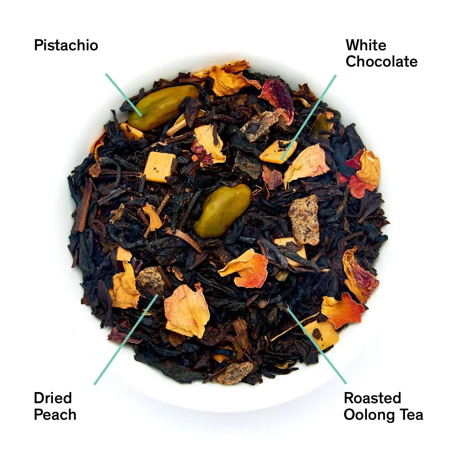 Close up of loose leaf Dark Iris tea showing roasted oolong leaves, dried peach pieces, whole pistachios, and white chocolate bits.
