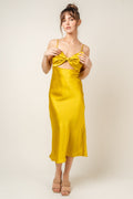 A woman wearing a vibrant yellow satin midi dress featuring a bow detail at the chest and a cut-out midriff, photographed from the front and back against a neutral background.