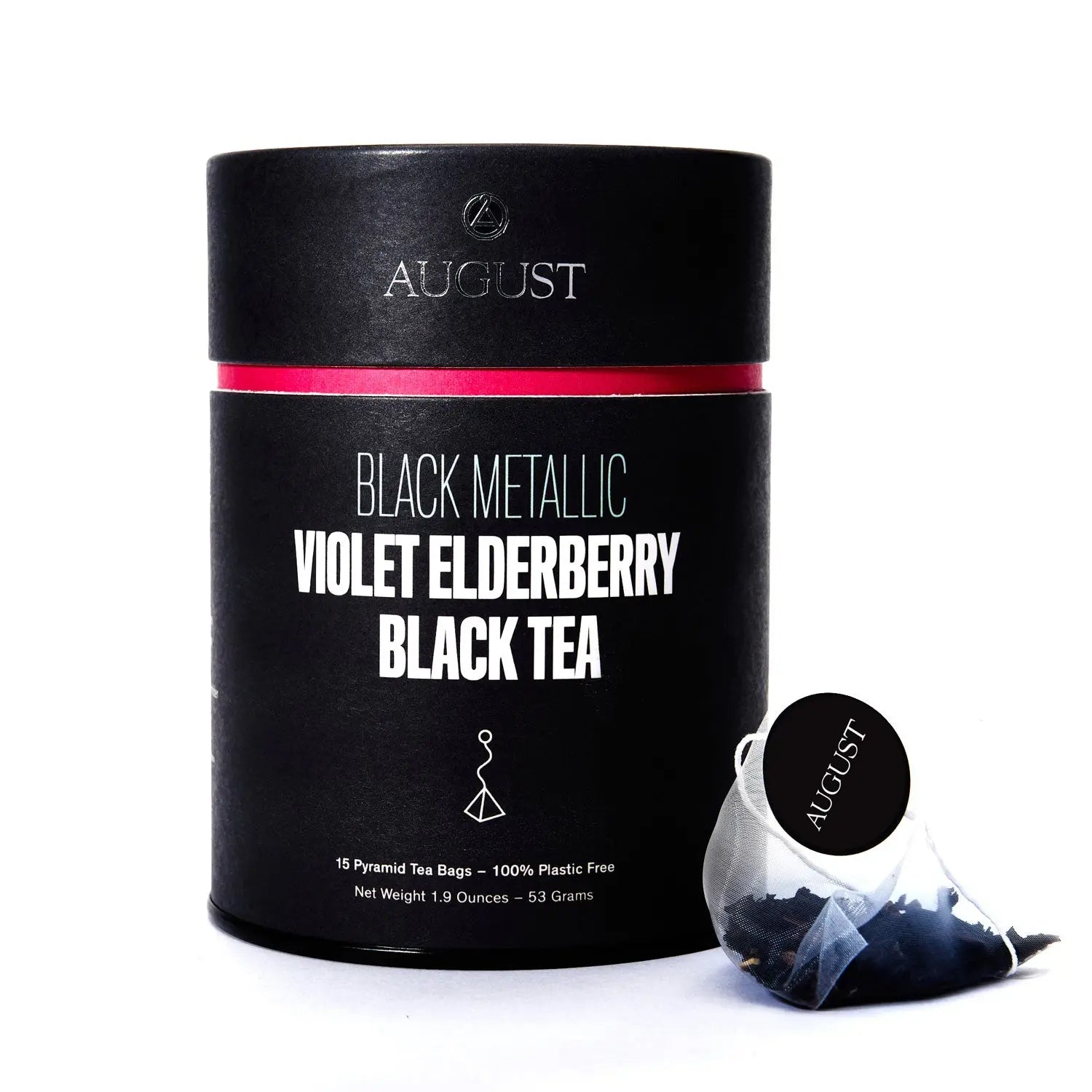A black cylindrical container of Black Metallic tea next to a single pyramid tea bag, alongside a bowl of the loose leaf tea blend showing dark tea leaves, blue cornflowers, and fruit bits.
