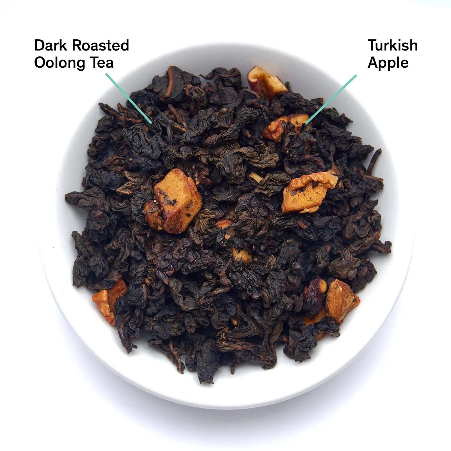 A bowl filled with Avalon burnt apple oolong tea leaves and dried apple pieces next to a black tea packaging bag.