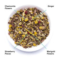 Bag of Nightfall herbal tea next to a bowl of dried chamomile, ginger, strawberry, and marigold ingredients.