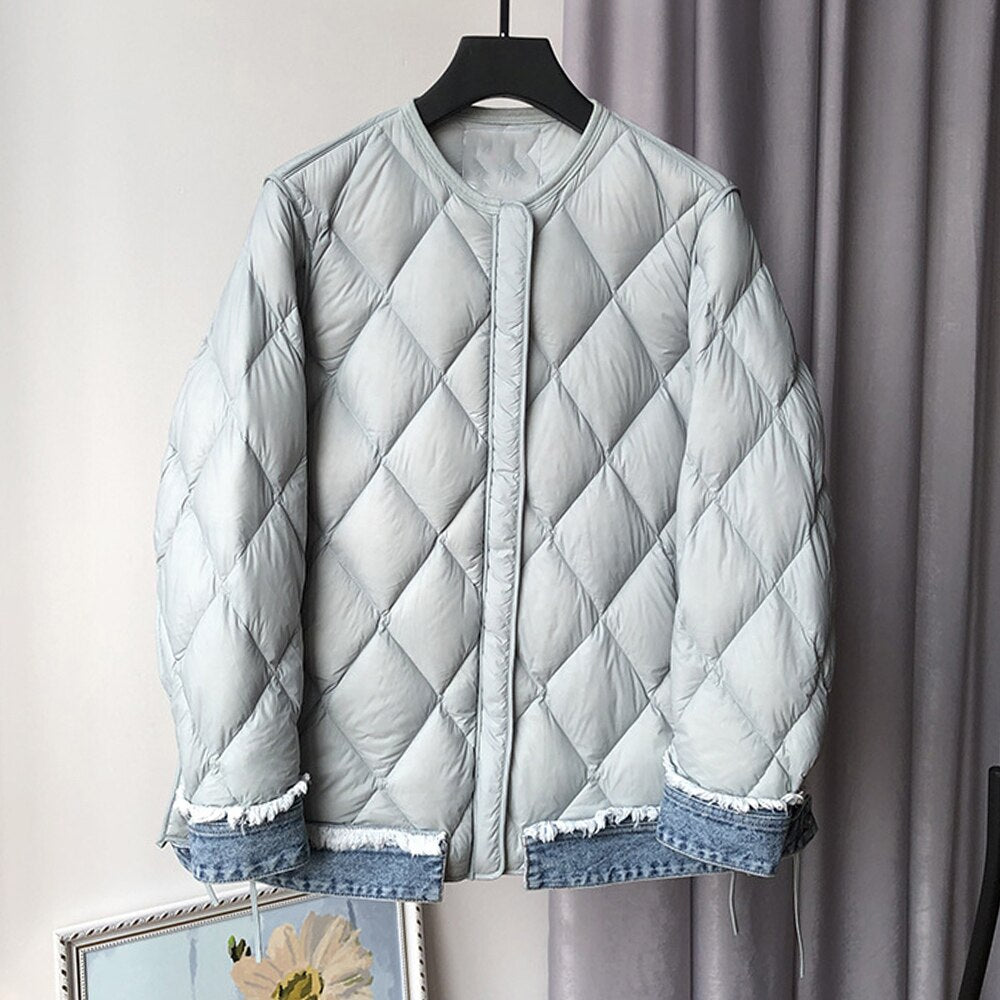 A light gray quilted cotton coat with blue denim patchwork trim on the cuffs and hem, featuring a round neck and button front.