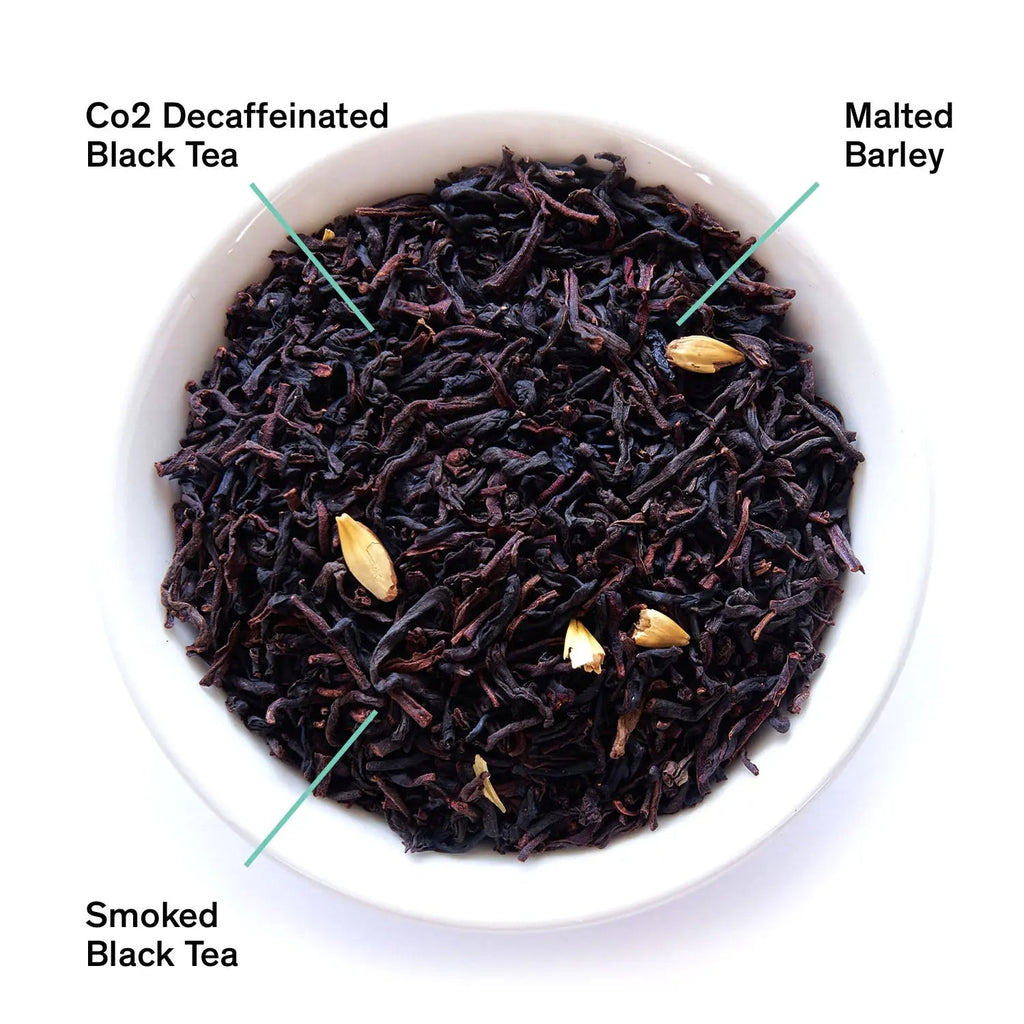 A bowl of dry loose leaf Decaf Low Country tea featuring black tea leaves and malted barley next to the product packaging.