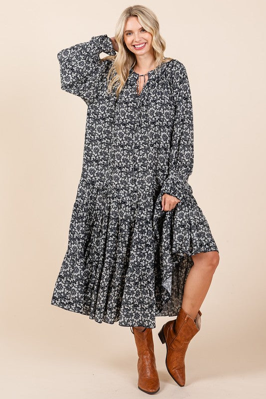 Woman wearing a printed midi dress featuring a tie-neck detail and feminine flounce sleeves.