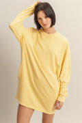A model wearing a bright yellow long sleeve oversized sweatshirt mini dress with a crew neck, styled with yellow checkered slip-on shoes.
