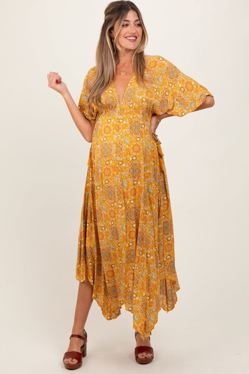 Yellow printed maternity maxi dress featuring a V-neckline and a flowy handkerchief hem.