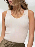 A woman wearing a minimalist oatmeal-colored V-neck sweater knit tank top in a casual setting.