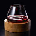 A crystal wine glass rotating on a wooden coaster, showcasing wine swirling inside for optimal aeration.