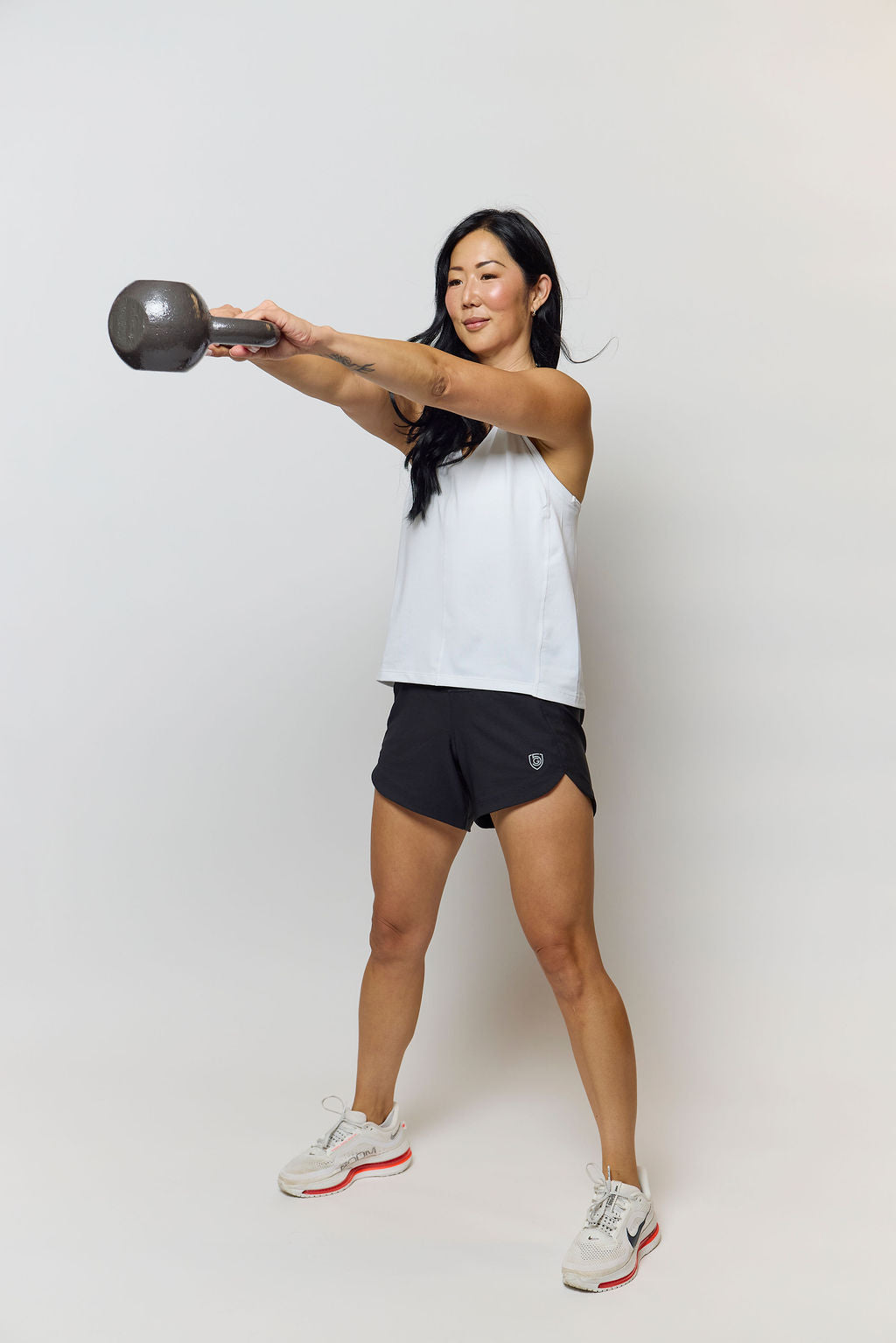 Woman wearing black Excel athletic shorts performing a squat in a gym setting
