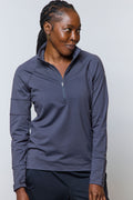 A woman wearing a dark grey half-zip long sleeve performance top with a stand-up collar.