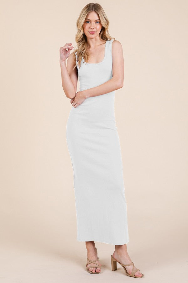 A woman wearing a fitted white ribbed sleeveless maxi dress with a scoop neckline.