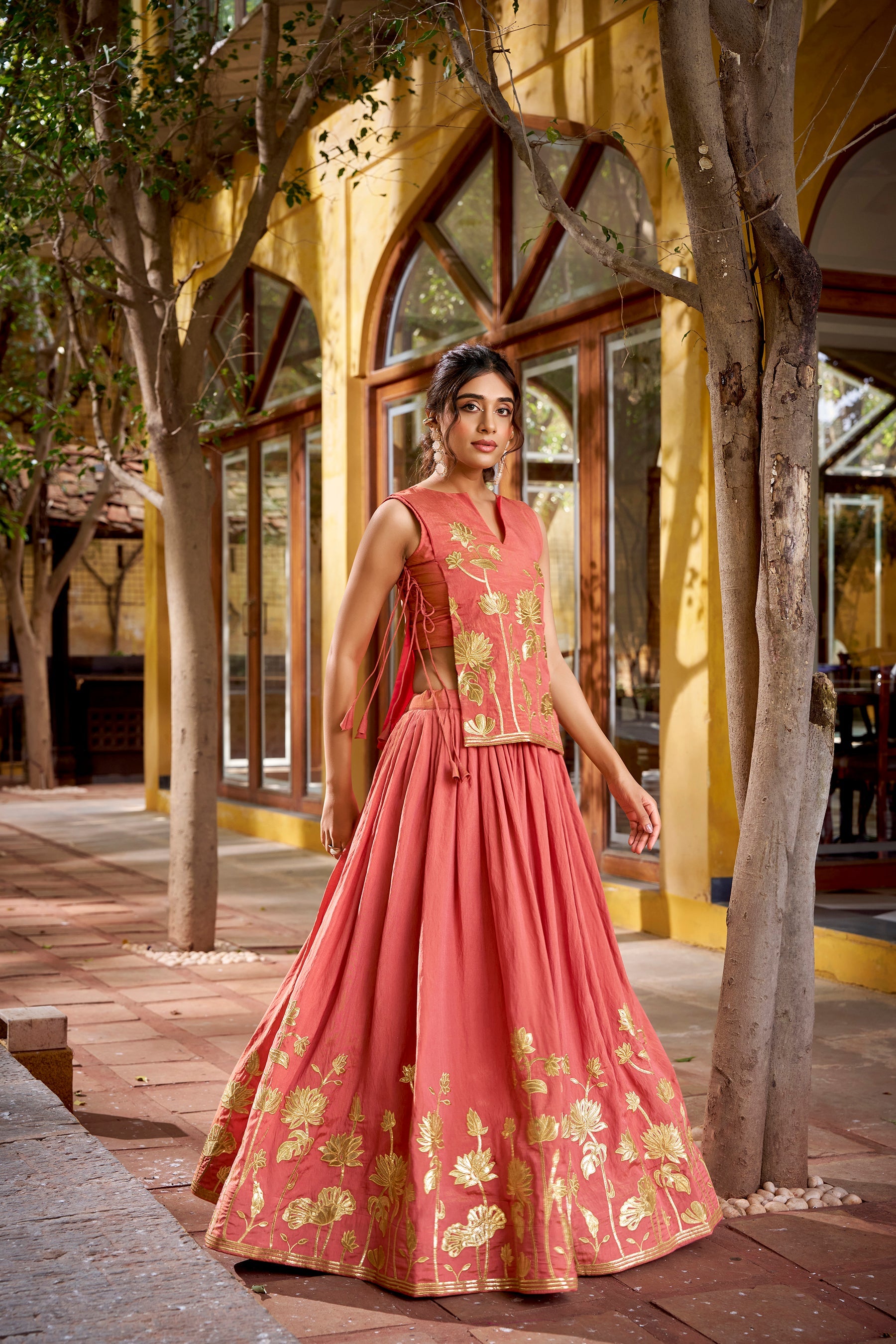 Woman wearing a rust-colored pure shimmer lehenga choli with detailed foil and thread embroidery
