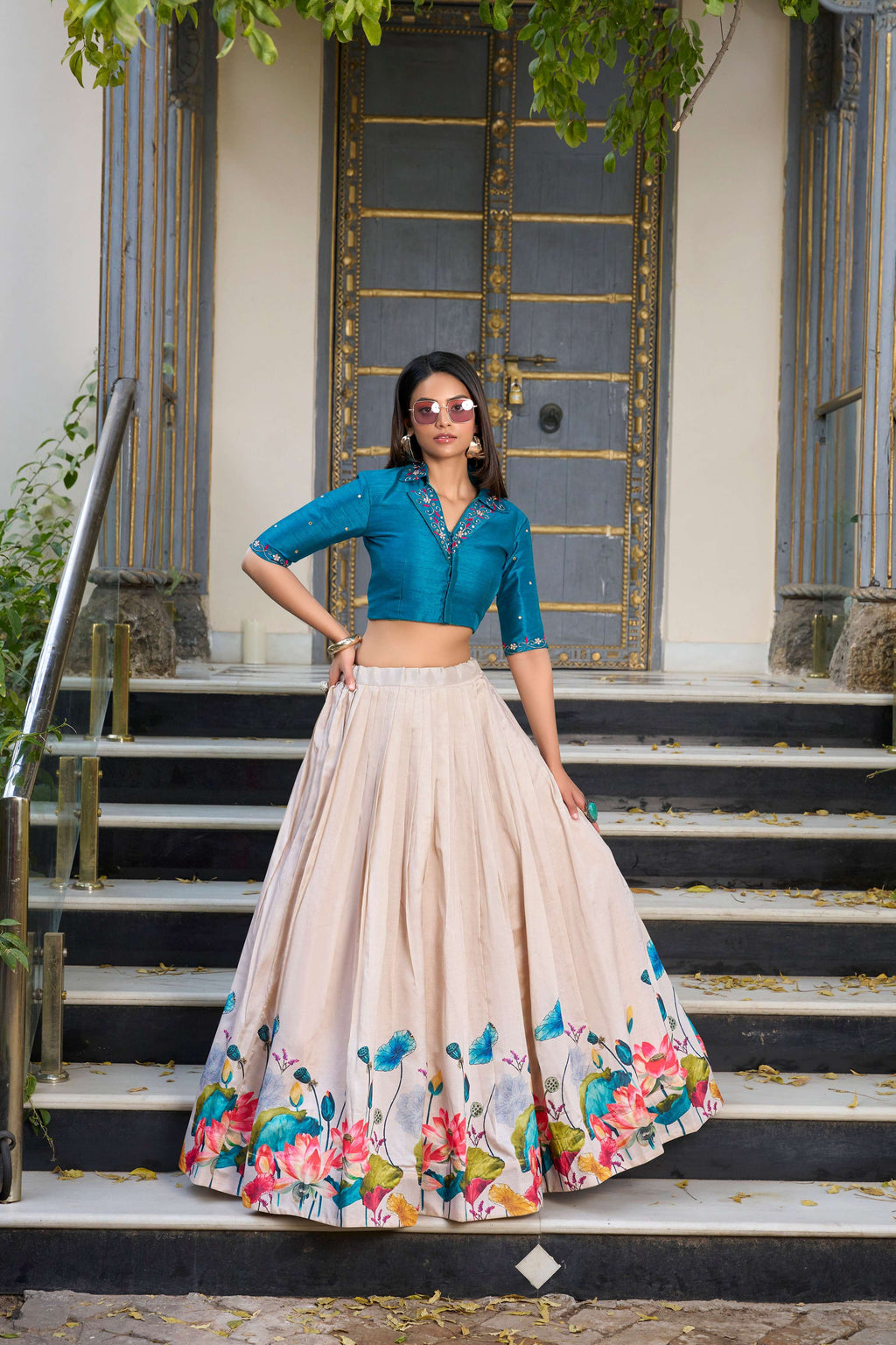 Model wearing an off-white Tussar silk lehenga choli with vibrant lotus floral prints and teal accents
