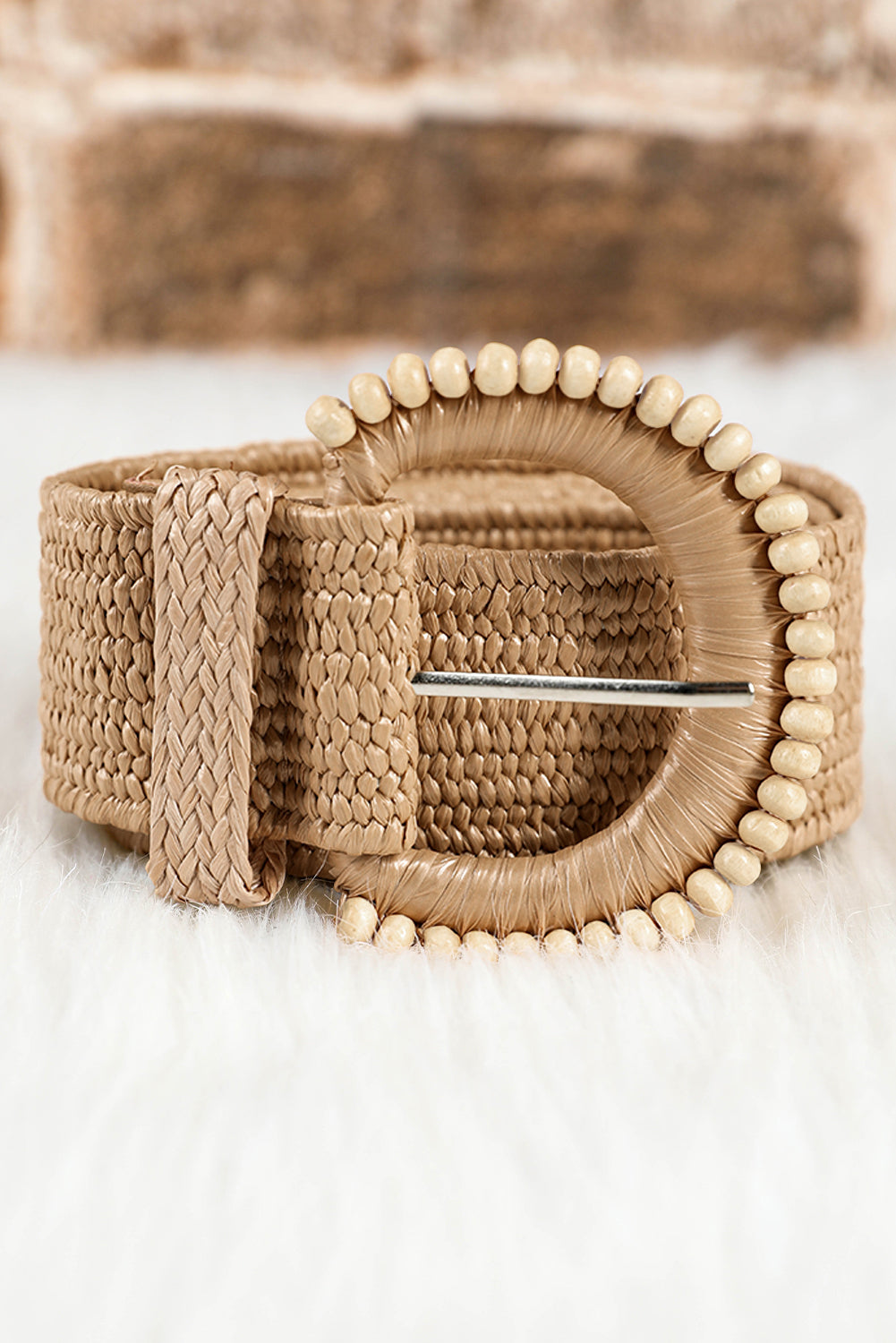 Close up of beige straw woven belt with delicate beaded details and pin-buckle closure, styled for a boho coastal look.