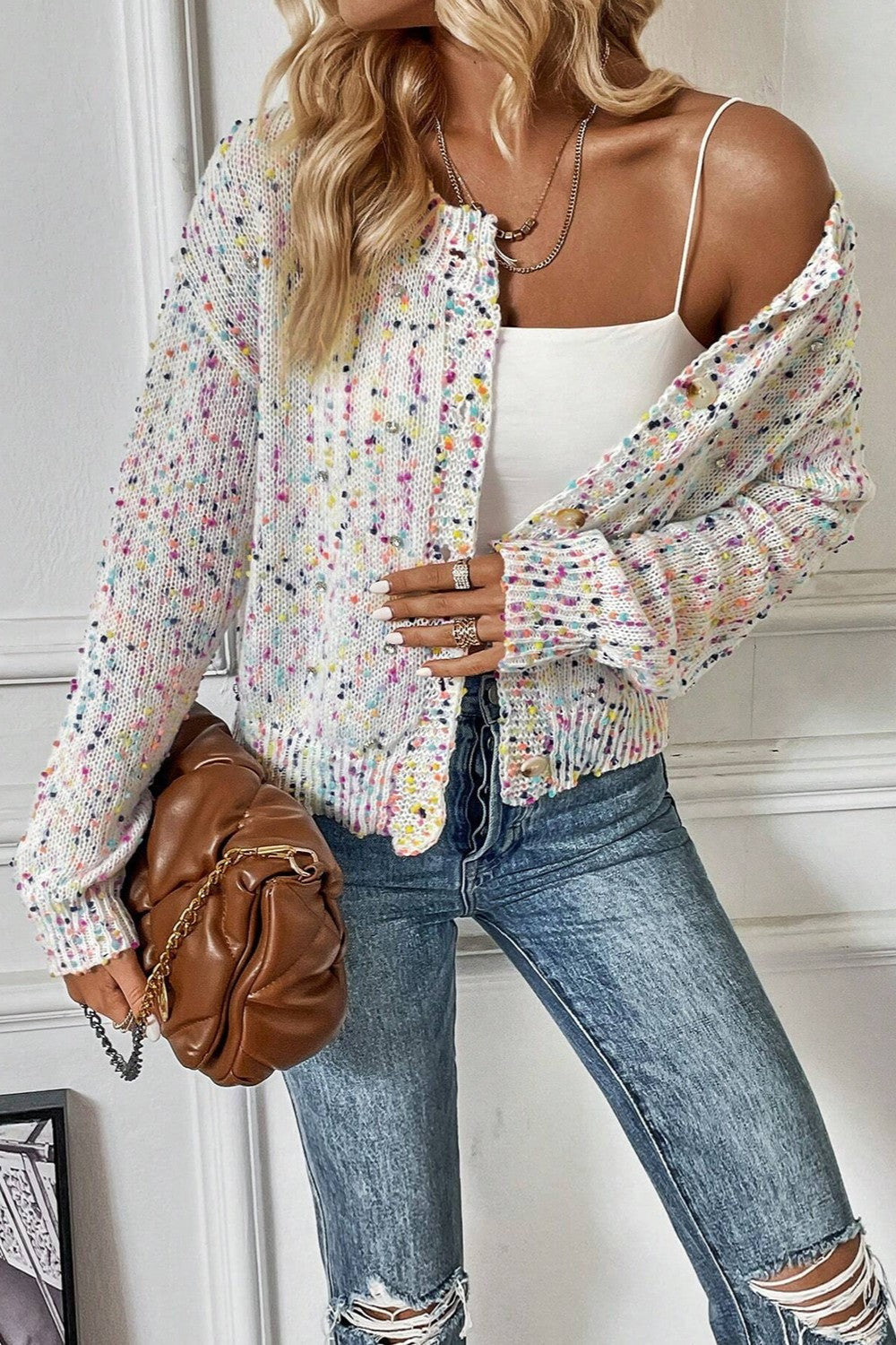 Woman wearing a white long-sleeve button-down cardigan with multicolored speckled confetti pattern