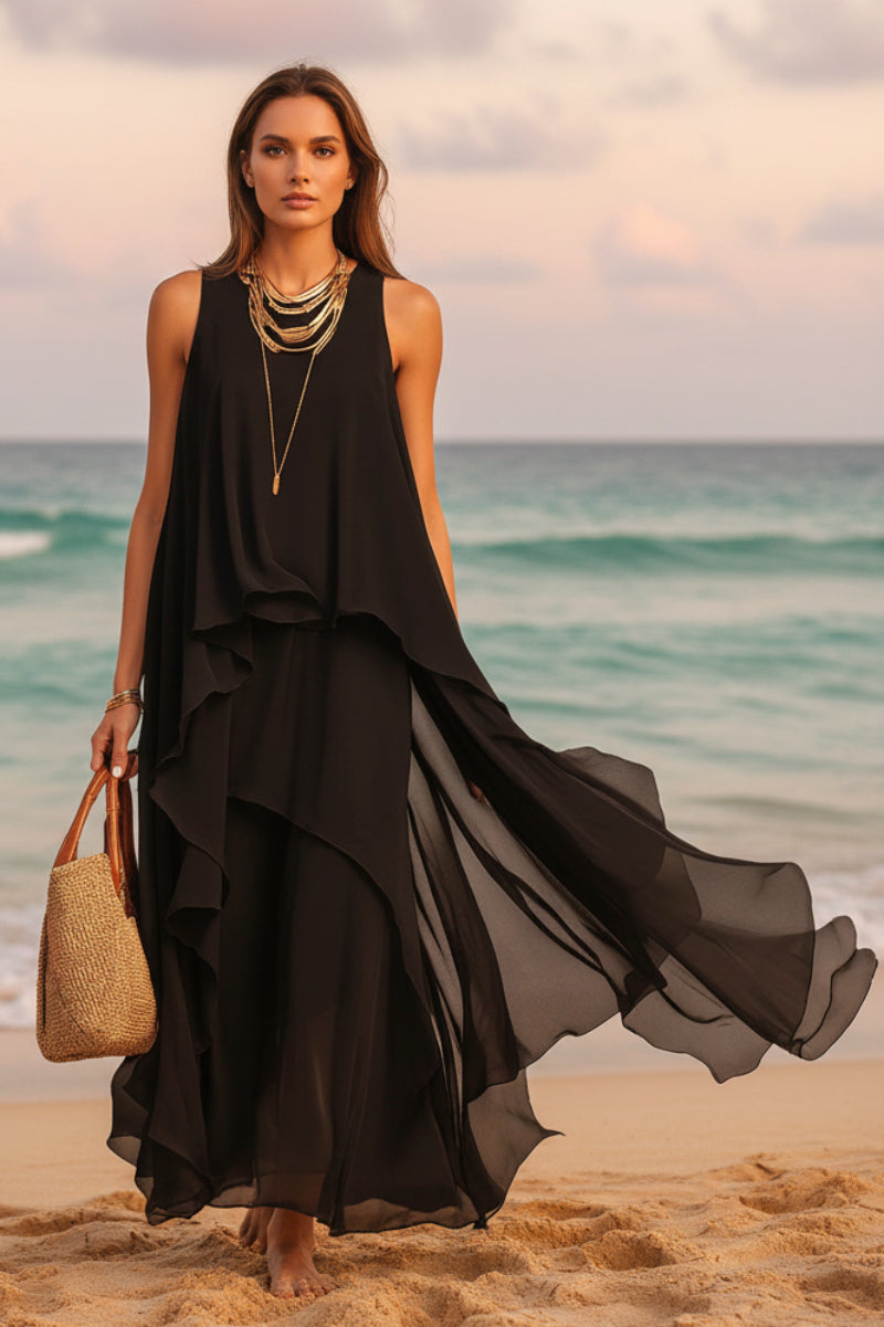 A woman wearing a sleeveless black asymmetrical chiffon maxi dress in a boho-inspired beach setting.