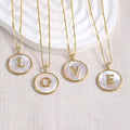 Close up of a Gold Shell Initial Pendant Charm on a delicate chain