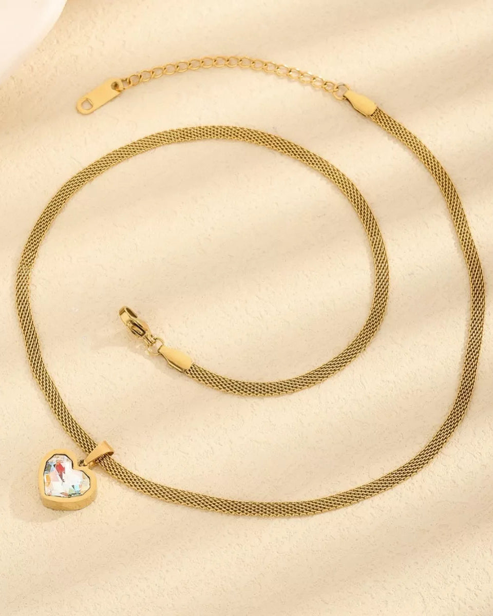 Gold necklace with a heart-shaped pendant on a beige background