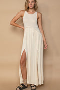 Model wearing a sleeveless racerback knit maxi dress with a front slit and back zipper detail