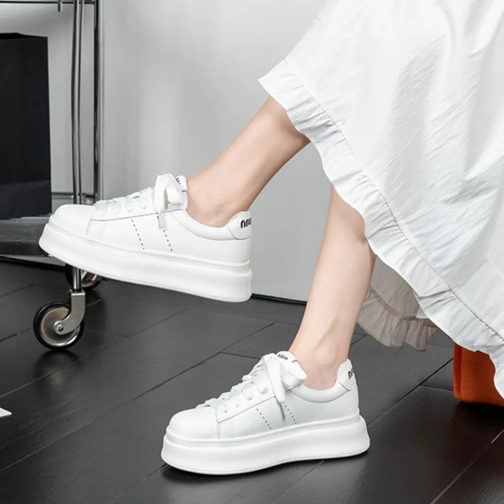 Pair of white lace-up platform sneakers on a model, showcasing the chunky sole and round toe design.