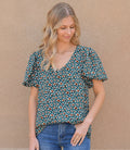 A kelly green printed short sleeve top with a V-neckline, shown in a studio setting.