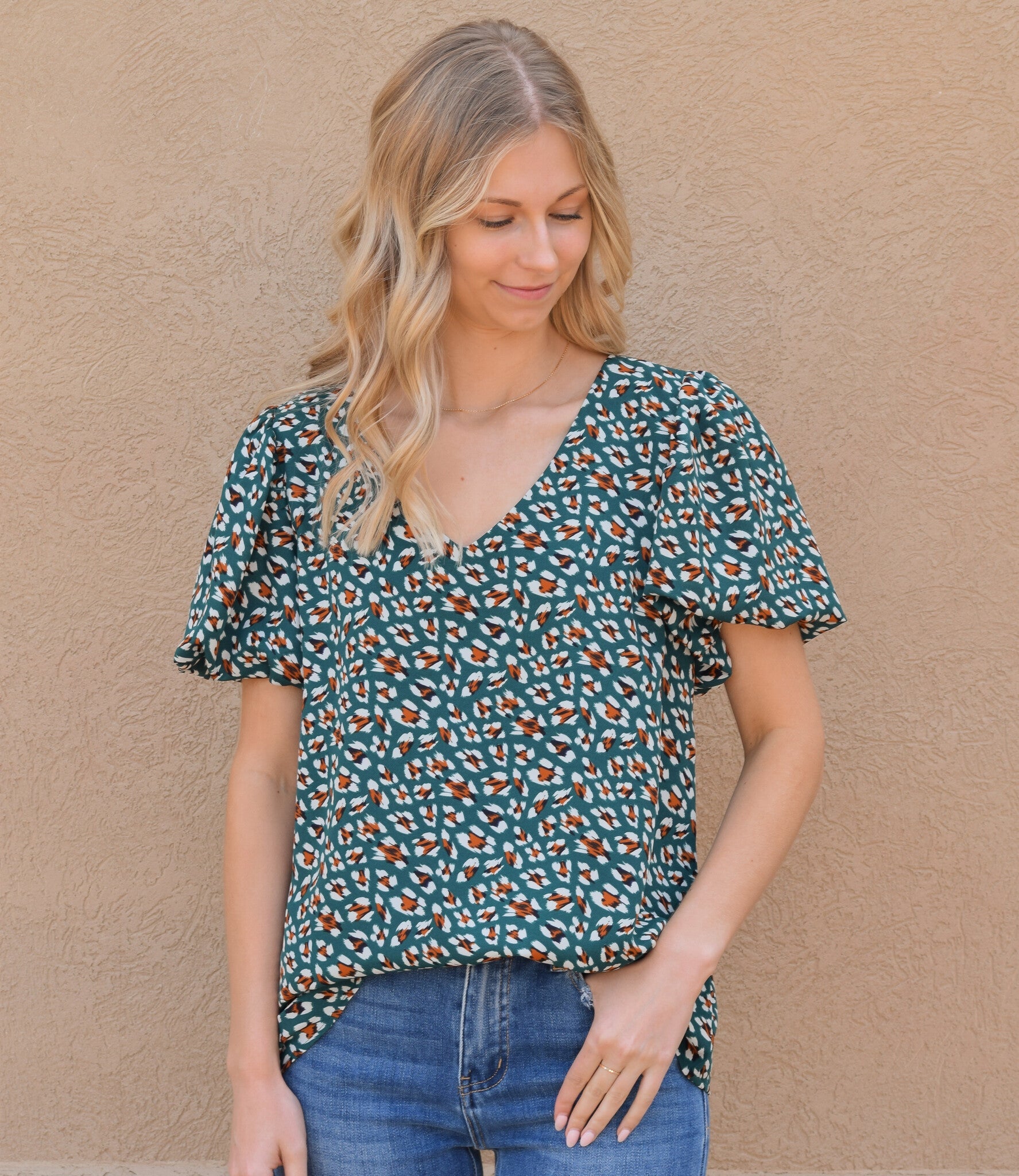 A kelly green printed short sleeve top with a V-neckline, shown in a studio setting.