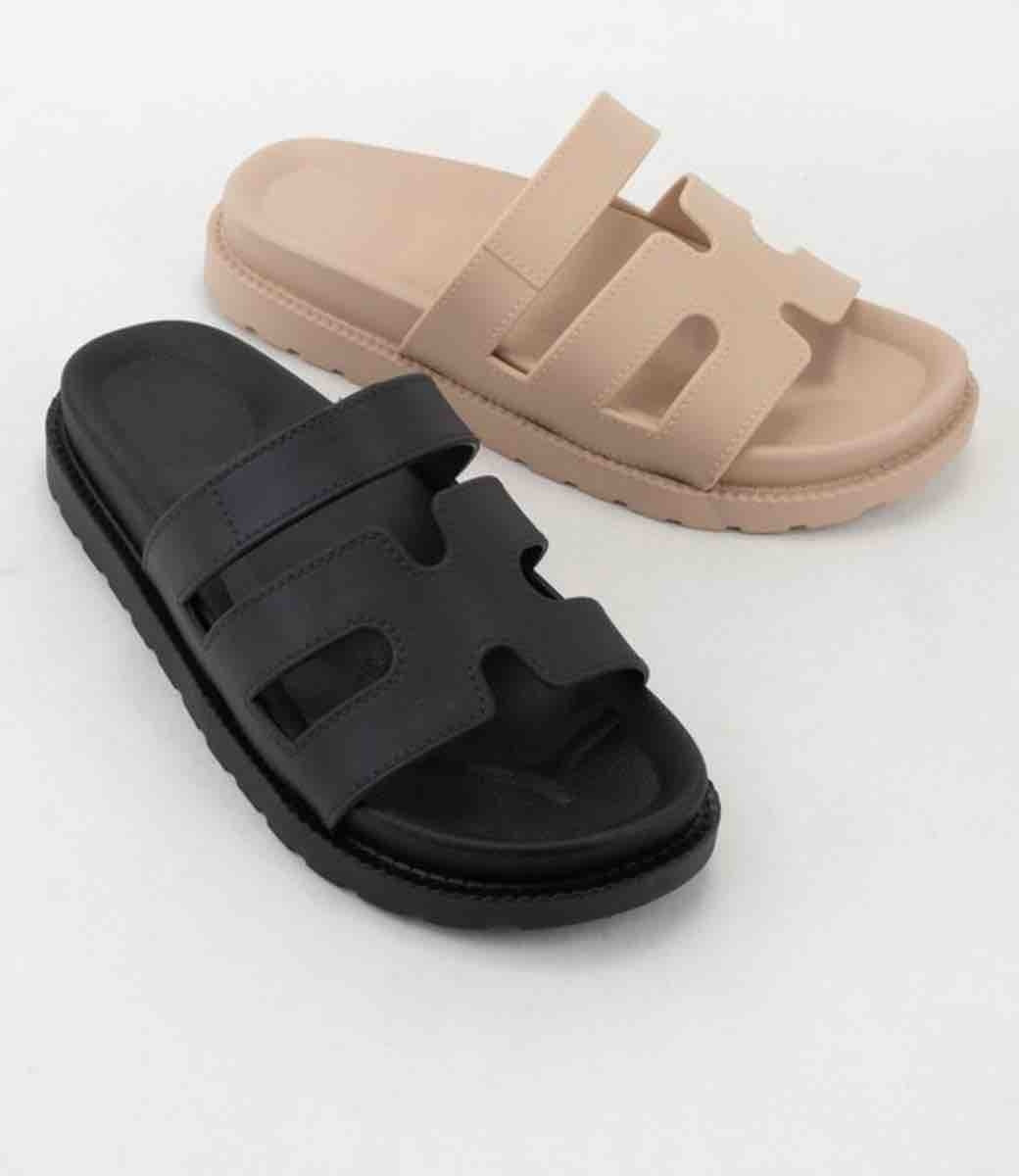 A pair of minimalist Gino Black sandals showing the cushioned footbed and sleek silhouette.