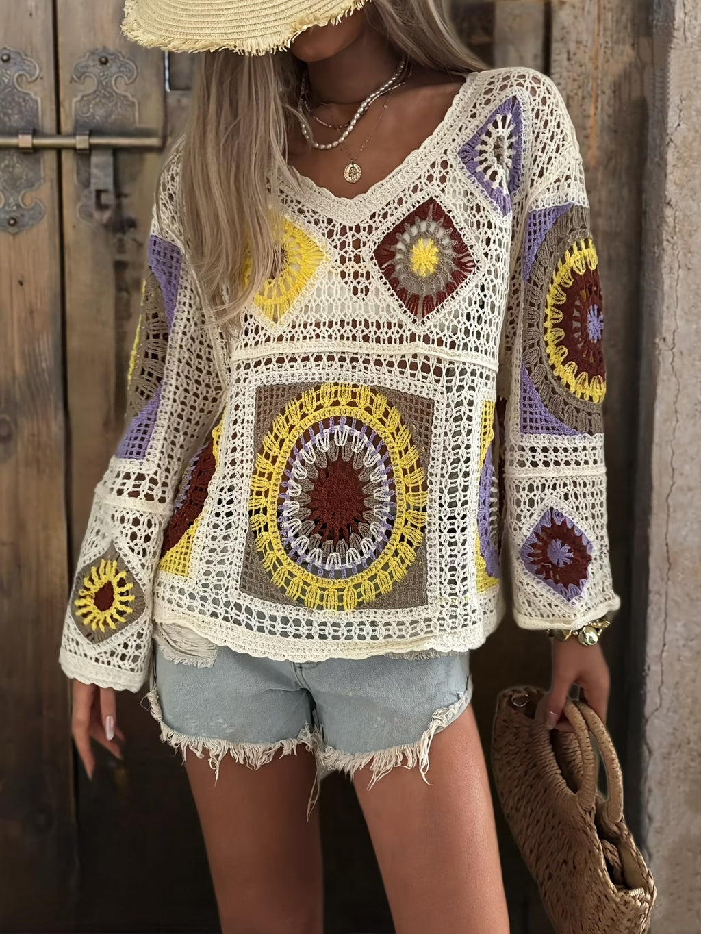 A woman wearing a long-sleeve multi-patterned crochet V-neck sweater with hollow-out design, styled for a boho vacation look.