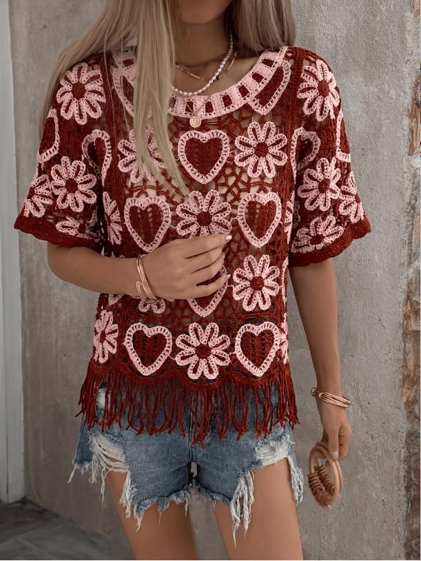 Woman wearing a boho-style beige open-work crochet pullover with fringe details and floral heart patterns.
