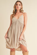 A beige ruched mini cami dress with a plunging neckline