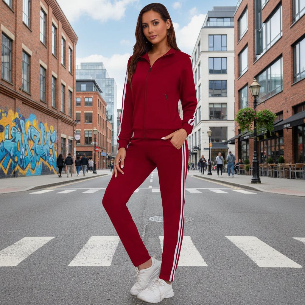 A woman wearing a matching women's red long-sleeve zip-up tracksuit with side-stripe detailing in an urban setting.