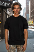 A man wearing a solid black heavy-duty cotton t-shirt with a classic crew neck.
