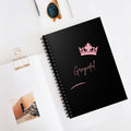 Minimalist spiral notebook featuring a black cover and pale pink graphic accents on a clean desk surface.