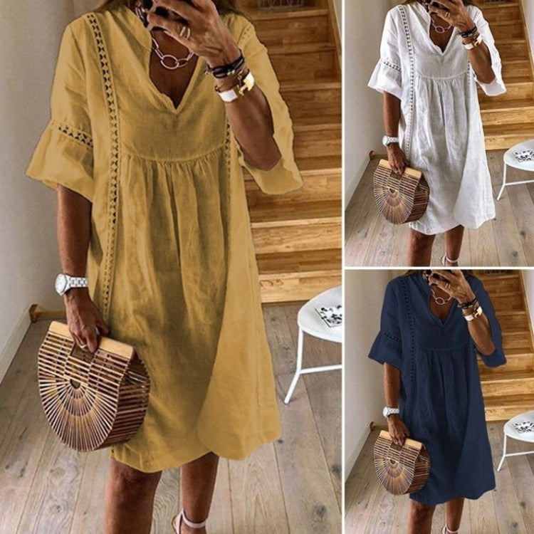 Woman wearing a linen V-neck A-line mini dress with lace stitching and flared sleeves